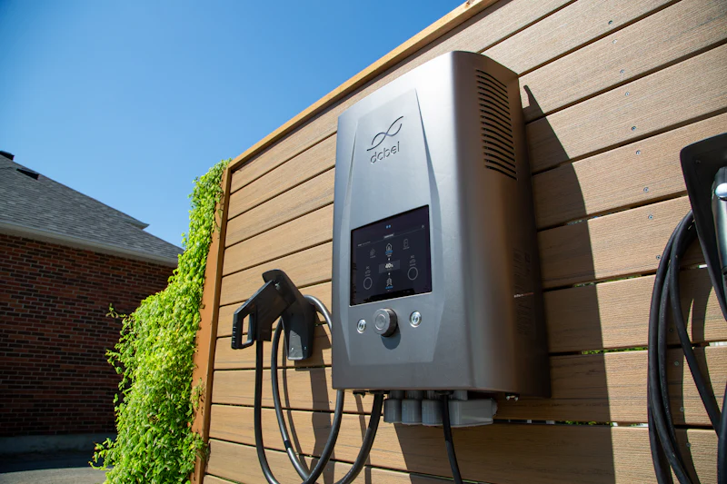 Laadpaal voor een elektrische auto aan een houten gevel